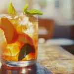 Sweet Peach Iced Tea in a glass with fresh peach slices and mint